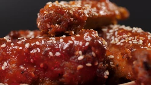 Chicken Wings Covered in Sauce and Sprinkled with Sesame Seeds in a Paper Bucket