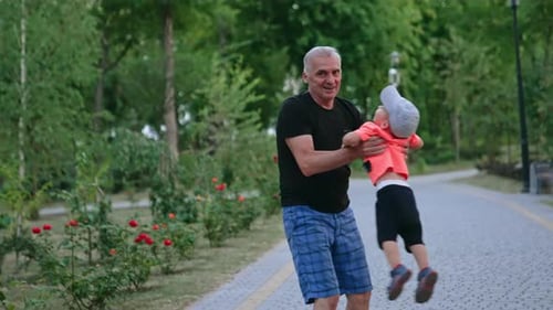 Un homme fait tourner le mignon petit garçon en casquette.