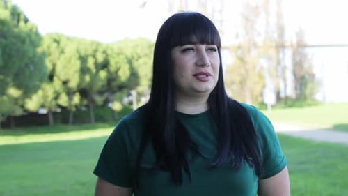 Expressive Woman with Black Hair Talking Outdoors in a Park