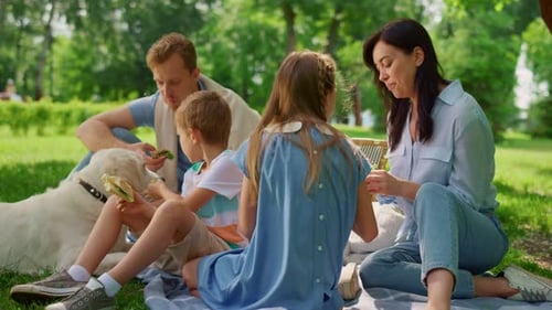 Family picnic outdoors with dog on blanket