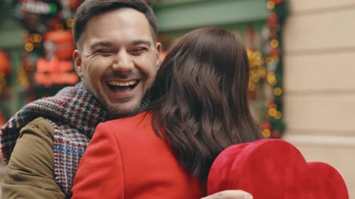 Man Hugs Woman with Gift on Christmas Street