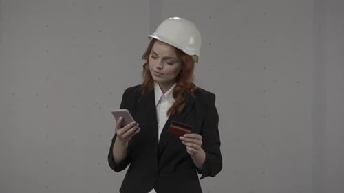 A Woman Architect Pays for a Purchase in an Online Store Using a Smartphone and a Credit Card