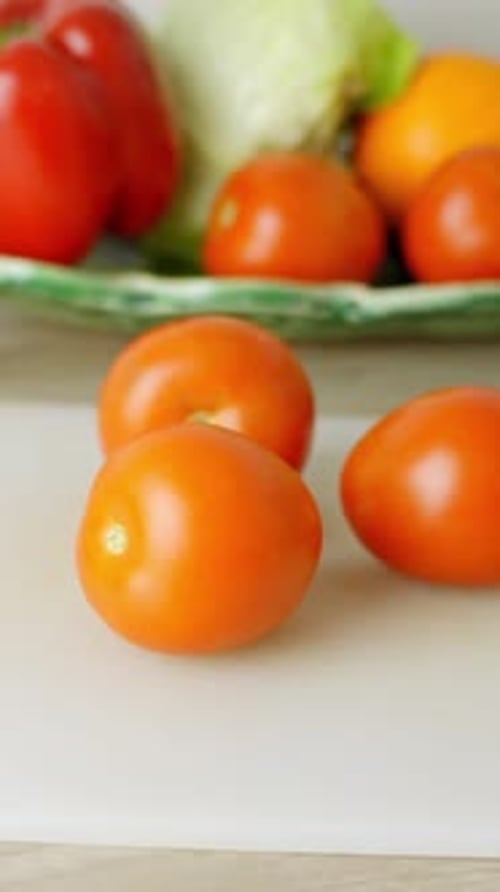 Ripe orange tomatoes on wooden cutting board in vertical bright kitchen pullback