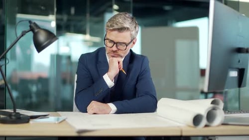 Industrial Design Engineering architect working on a Blueprints in office. Mature man real estate