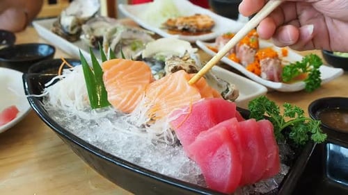 Close Up of Person Eating Sashimi with Chopsticks