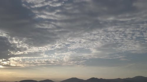Tilted up, pan Dusk shot of a sky with Mountain in far distance. Sunset sky above dark mountains