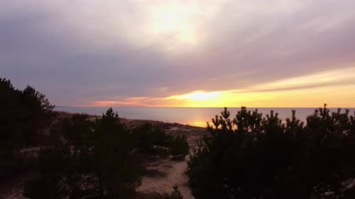Sunset through cloudy sky near sandy beach, aerial view