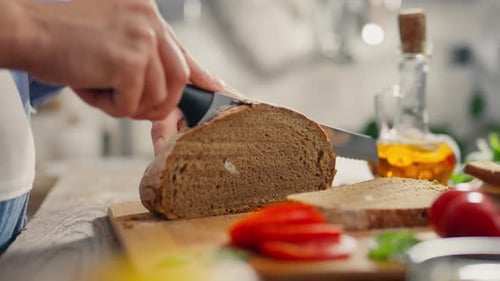 Woman Slices Dark Bread on Cutting Board