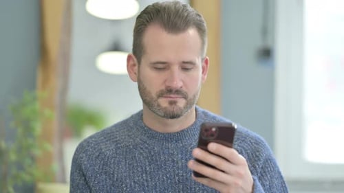 Bearded Man Using Smartphone in Interior Setting