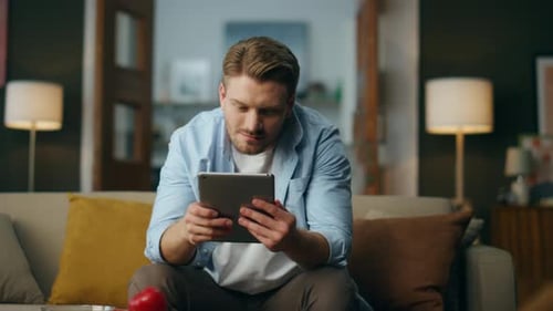 Positive Man Using Tab Computer at Home Optimistic Guy Working Pad Sitting Sofa