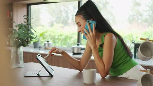 Woman Talks on Phone, Uses Stylus on Tablet