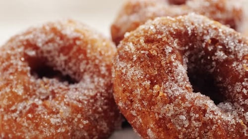 Traditionelle spanische Donuts mit bunten Streuseln, Nahaufnahme von rosafarbenen Süßigkeiten, Lebensmittelmakro