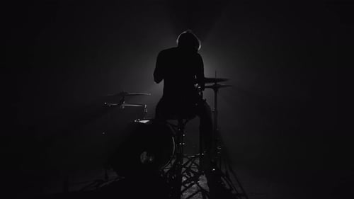 Silhouette eines männlichen Schlagzeugers, der im Dunkeln Schlagzeug spielt
