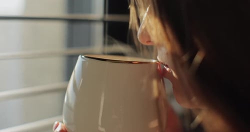 Close Up of Woman Standing Near Window Holding Coffee Cup at Sunrise Woman Enjoying Cup of Coffee