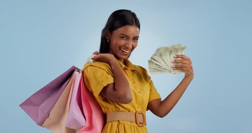Happy woman, money fan and shopping bags for payment, buying or purchase against a studio