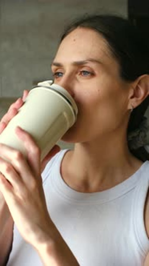 Smiling Woman Drinks From Reusable Cup Indoors