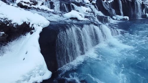 Waterfall in Iceland Frozen Snowy Mountain with Cold River in Winter Aerial