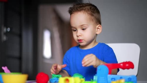 Focused Child Playing with Colorful Modeling Clay at Table