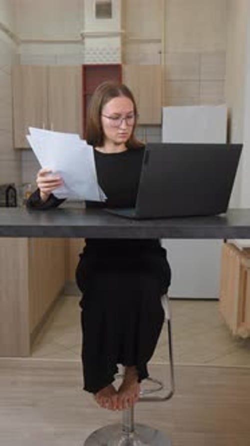 Businesswoman comparing documents working at laptop computer