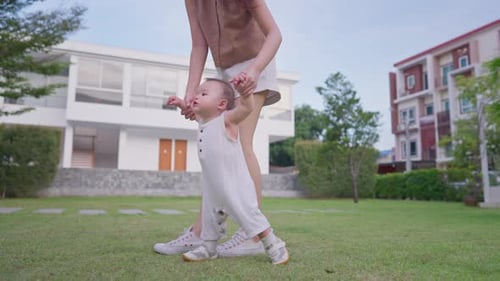 Close up of mother lovingly care for their baby boy outdoors in park.