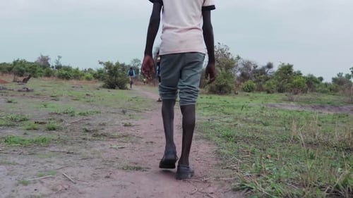 Afrikanisches Kind läuft in einer Flüchtlingssiedlung zur Wasserquelle.