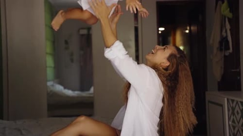 Glückliche Mutter spielt mit ihrer lachenden Tochter und teilt einen verspielten und liebevollen Moment in einem gemütlichen Heimset
