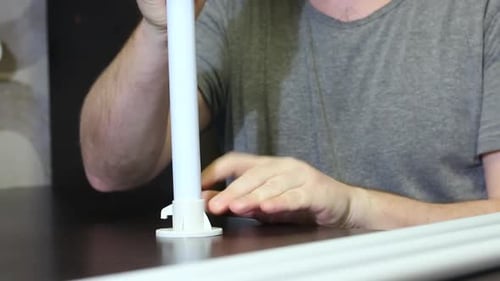 Un homme montre des pièces pour un auvent de jardin. Connecte les tubes et les adaptateurs. Prise de vue rapprochée.