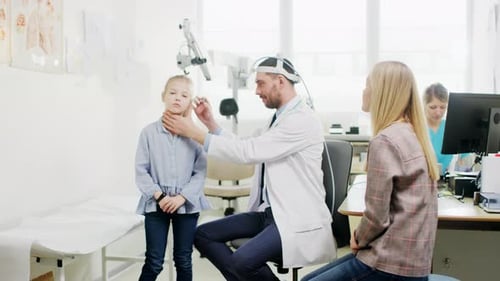 Mother with a Little Daughter Visit Doctor. Friendly ENT Pediatrician Checks Ears of a Little Smili