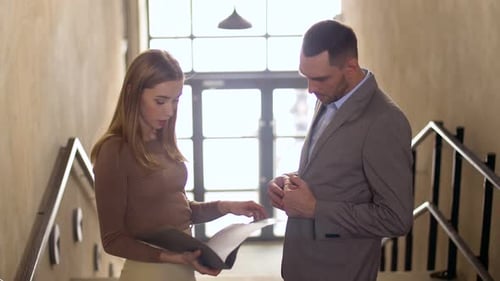 Businesswoman and businessman discussing documents in the office stairway