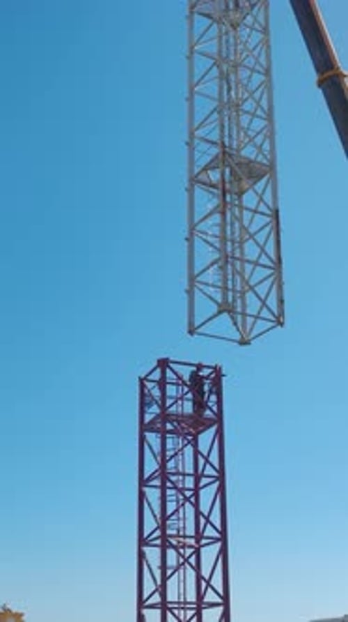Vídeo vertical: Ingenieros expertos construyen una grúa torre pieza por pieza en una construcción vibrante