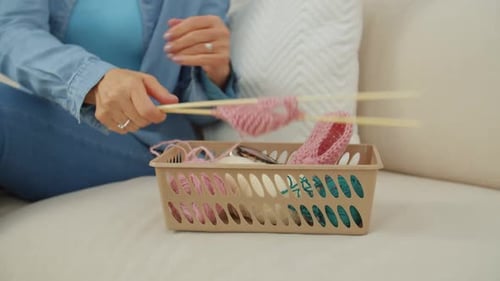 Woman Knitting Pink Yarn at Home on Couch