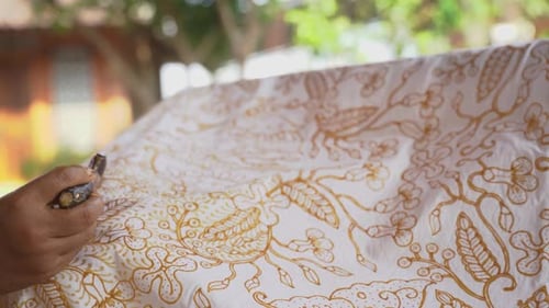 The technique of making hand-drawn batik using a canting tool. This craftsman is making batik typica
