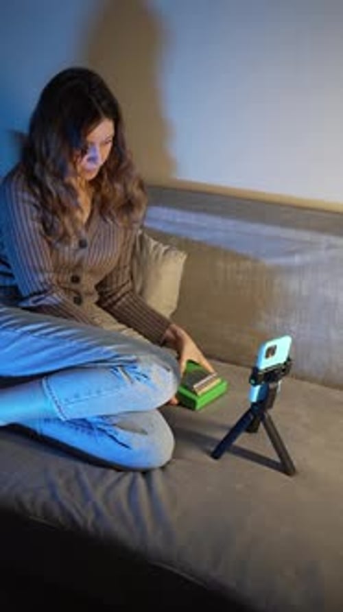 Woman playing kalimba, recording video on phone indoors