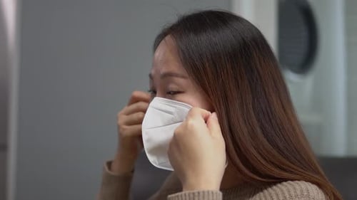 Woman Puts on White Protective Face Mask