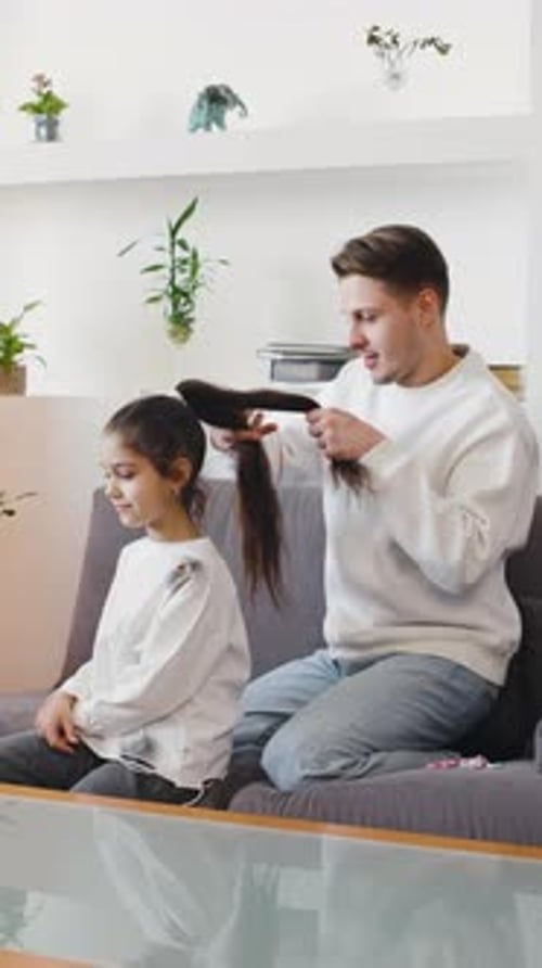 Man fixes girls hair inside modern home