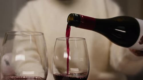 Unerkennbare Person, die ein Glas Wein einschenkt