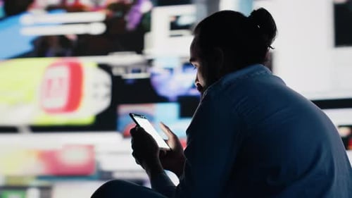 Man Using Mobile Phone in Front of Screen