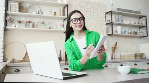 Portrait of dark haired student with eyeglasses have a remote lesson, talking with teacher, showing