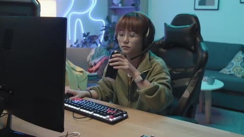Chinese Girl Playing Videogame and Sipping Energy Drink