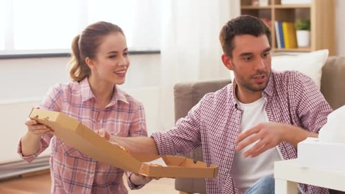 Couple eats pizza together in their living room