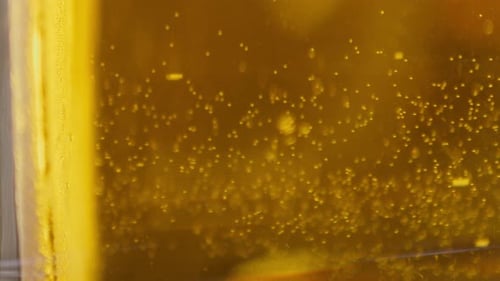 Extreme Close up of craft Beer bubbles floating to the top of a pint glass with foam VERTICAL