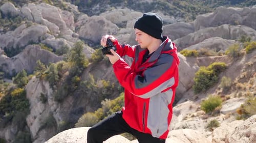A wildlife photographer and his camera in winter gear looks out at the California mountain landscape
