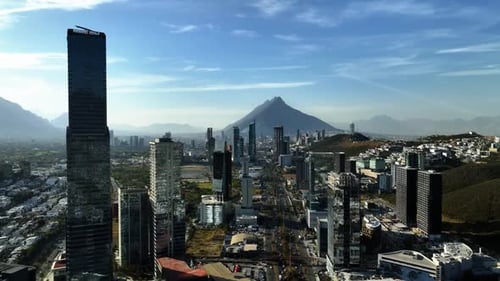 Aerial wide shot of urban city skyline and mountain peak