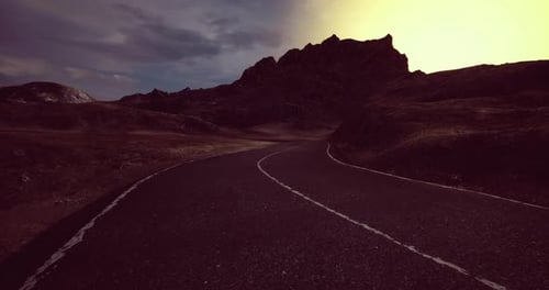 Winding Road Through Mountainous Terrain During Twilight in a Remote Location