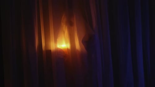 Candle Glowing Behind Opaque Bedroom Curtains at Night