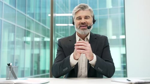 Webcam view. Confident businessman in headset talking on video call looking at camera sitting