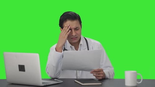 Confused Indian doctor checking medical reports Green screen