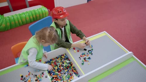 Two Kids Wearing Waistcoats Playing with Colorful Blocks in Educational Games Center Top View Slow