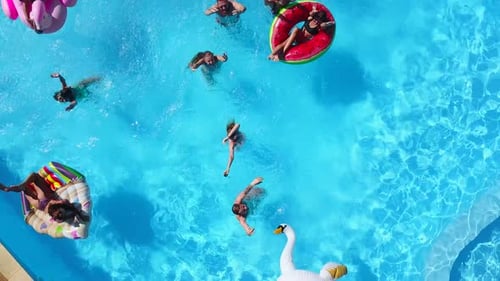 Vue aérienne d'amis faisant la fête dans la piscine avec matelas gonflable Flamingo Swan Happy Young