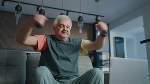 Elderly Man Watching Video On Laptop Display And Training With Dumbbells At Home Online Workout
